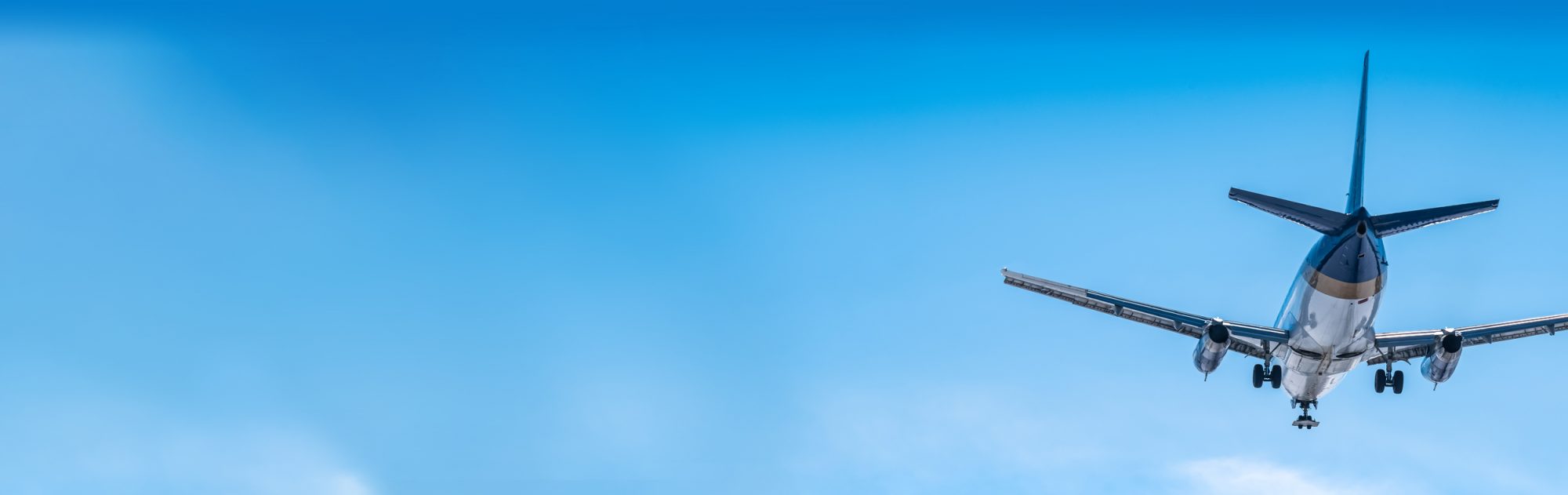 Un avion survole un ciel bleu clair, se dirigeant vers l'atterrissage avec ses ailes étendues.