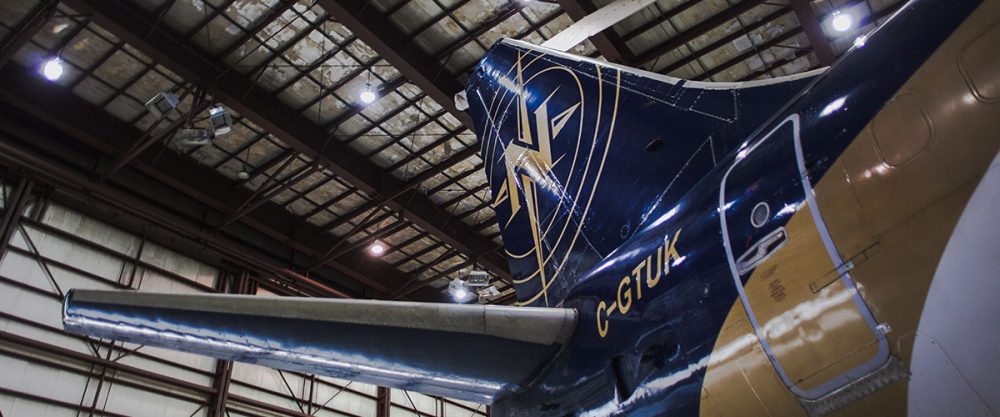 Un avion est stationné dans un hangar, mettant en avant sa queue et ses ailes. Le logo de la compagnie est visible sur la dérive.
