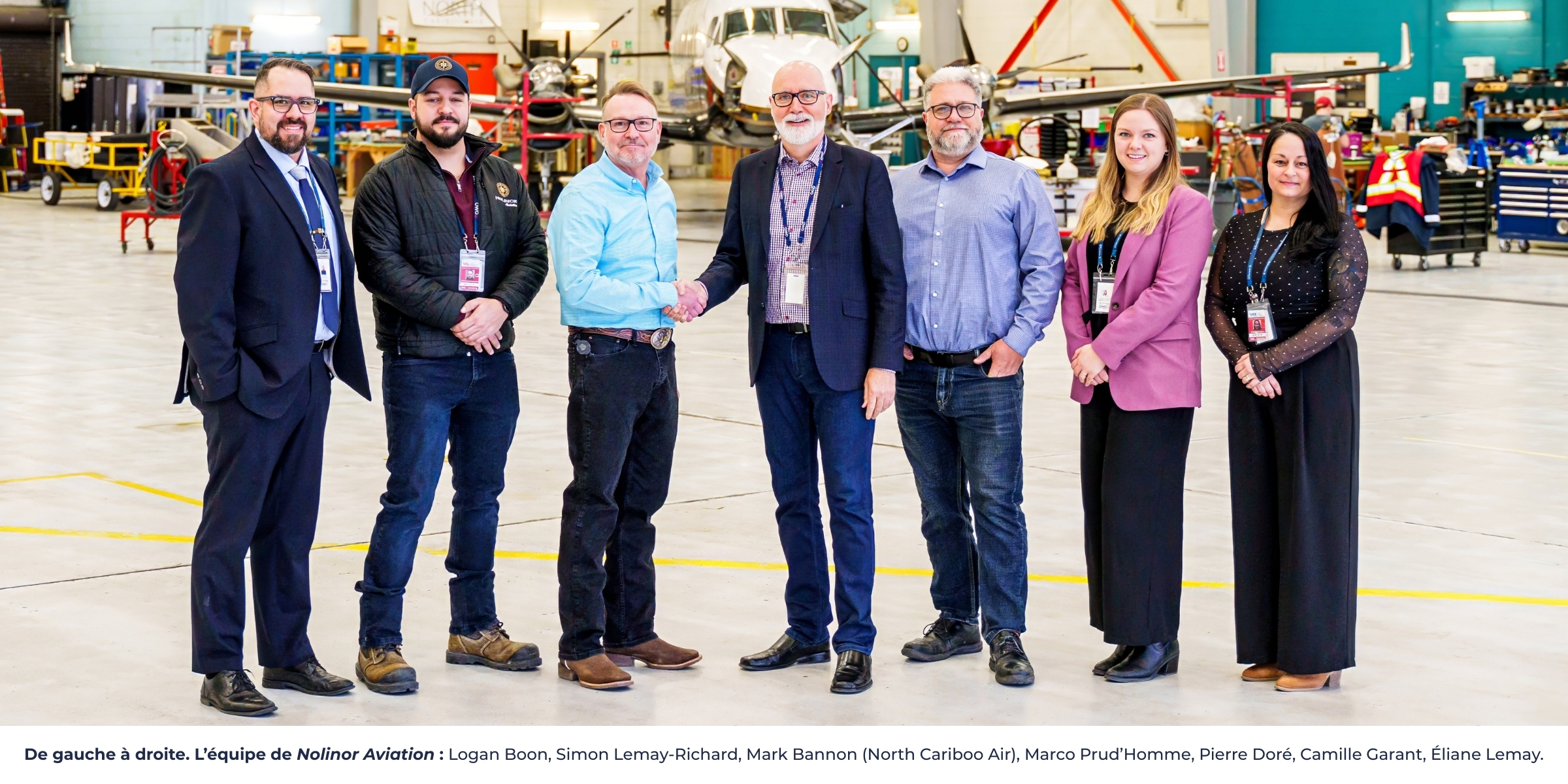 L'équipe de Nolinor Aviation se tient dans un hangar, souriante, après une remise de prix. Des avions sont visibles en arrière-plan.