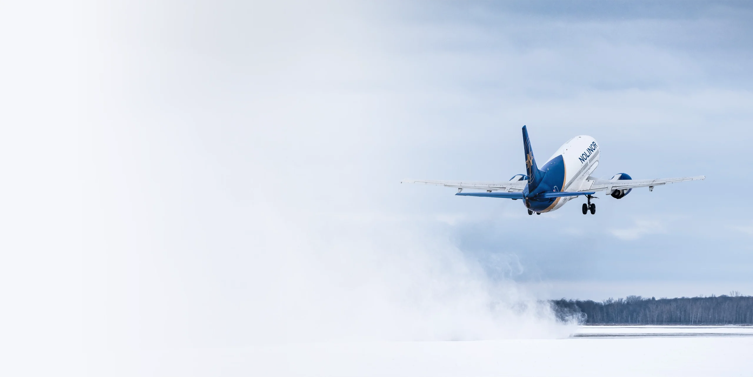 A Nolinor airplane takes off against a cloudy sky, leaving a trail of mist behind as it ascends.