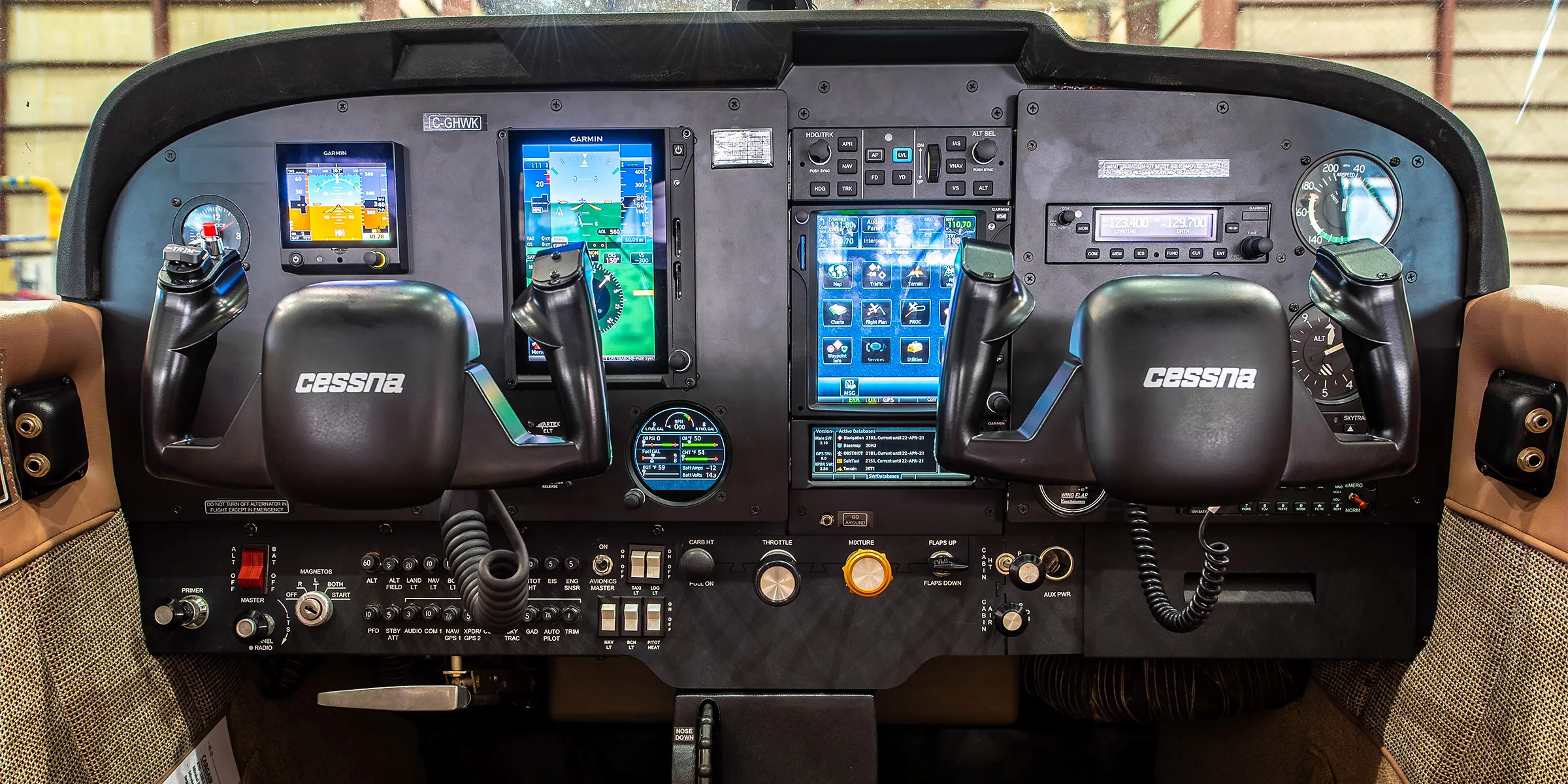 Cockpit view of a Cessna aircraft featuring multiple digital displays, control yokes, and various instrument panels.