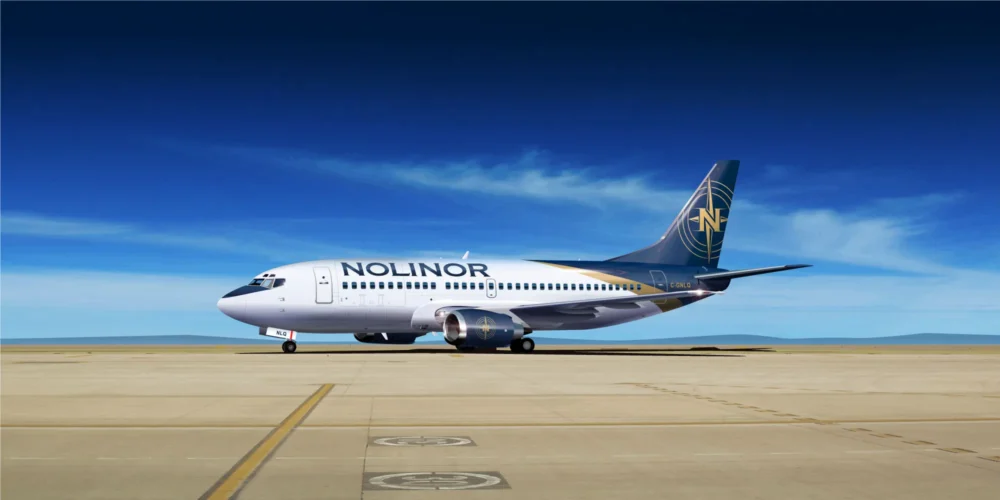 Un avion de la compagnie Nolinor est stationné sur un tarmac sous un ciel bleu dégagé, prêt pour le décollage.